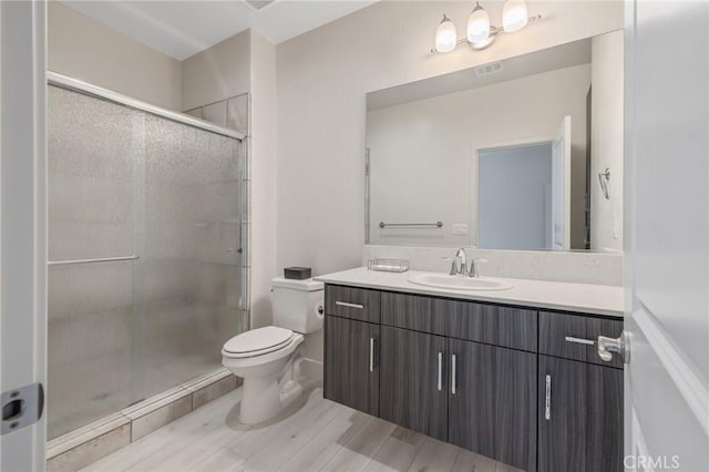 full bathroom with a stall shower, toilet, visible vents, wood finished floors, and vanity