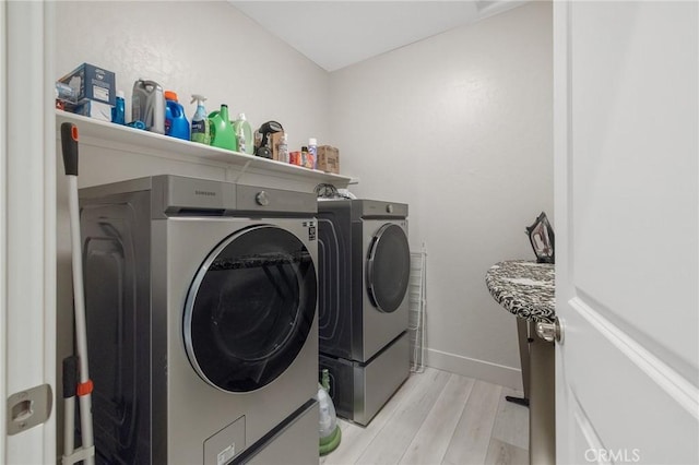 laundry room with separate washer and dryer, baseboards, laundry area, and light wood-style flooring