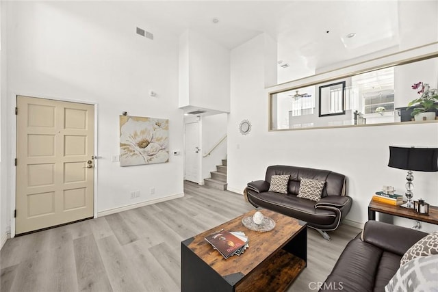 living area with wood finished floors, visible vents, a towering ceiling, and stairway