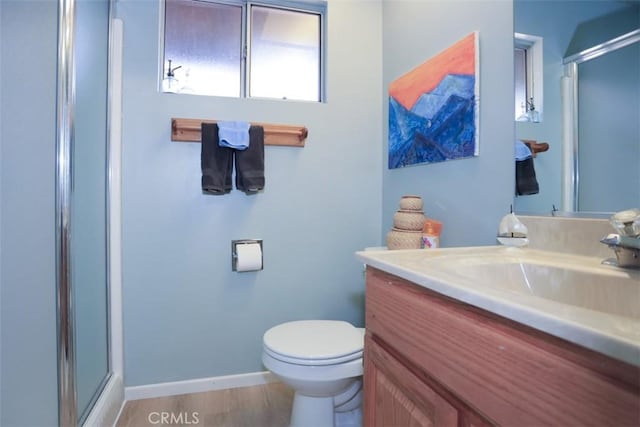 bathroom with a shower stall, toilet, vanity, and baseboards