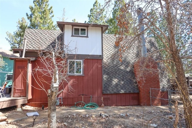 view of side of property with roof with shingles and fence
