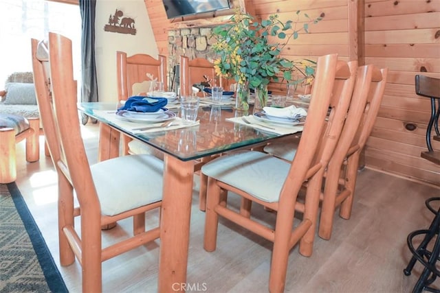 dining area with wood finished floors and wood walls