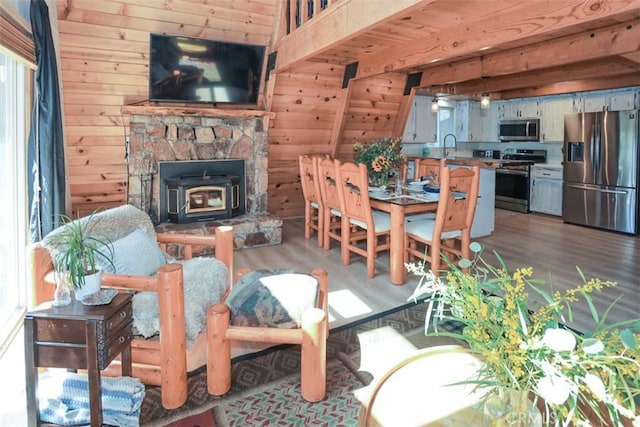 dining area featuring light wood-style flooring, wooden walls, and a wood stove