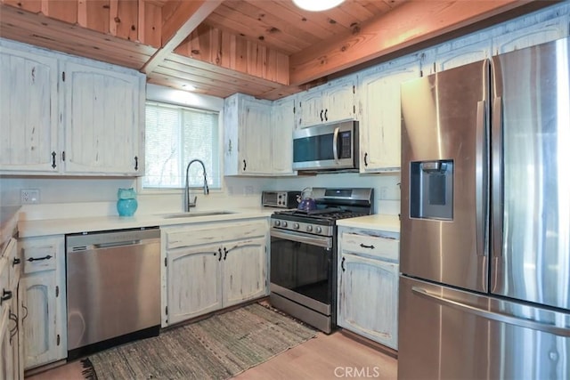 kitchen with stainless steel appliances, light countertops, wooden ceiling, a sink, and light wood-type flooring