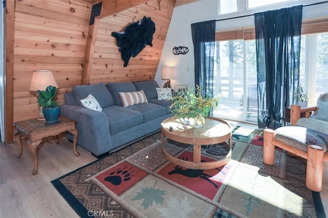 living room with wooden walls, wood finished floors, and a healthy amount of sunlight