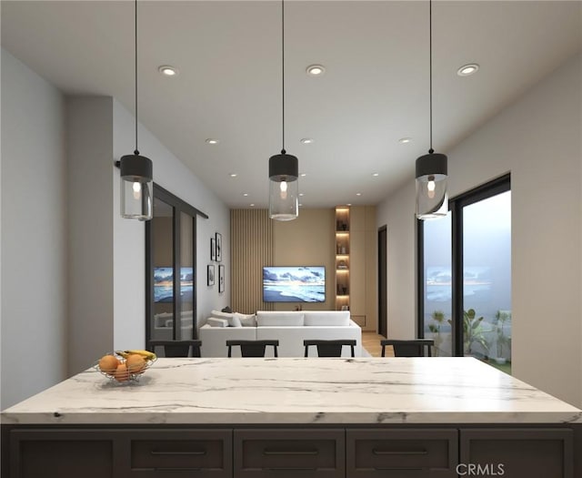 kitchen featuring recessed lighting, light stone counters, decorative light fixtures, a kitchen island, and open floor plan