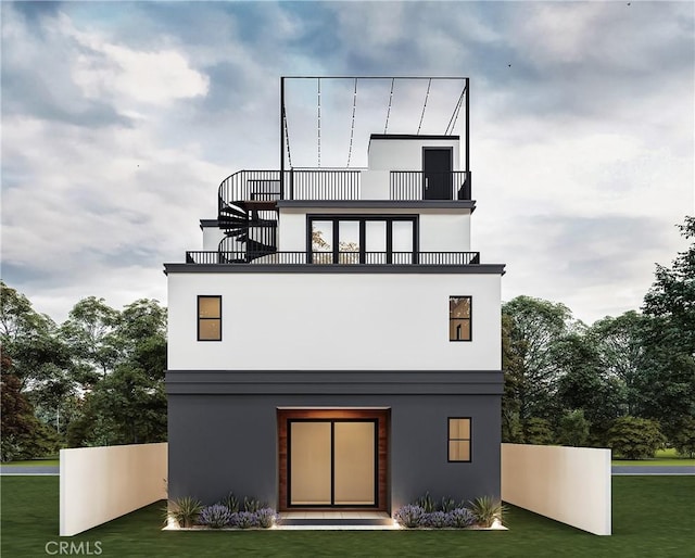 back of house featuring a lawn, a balcony, and stucco siding