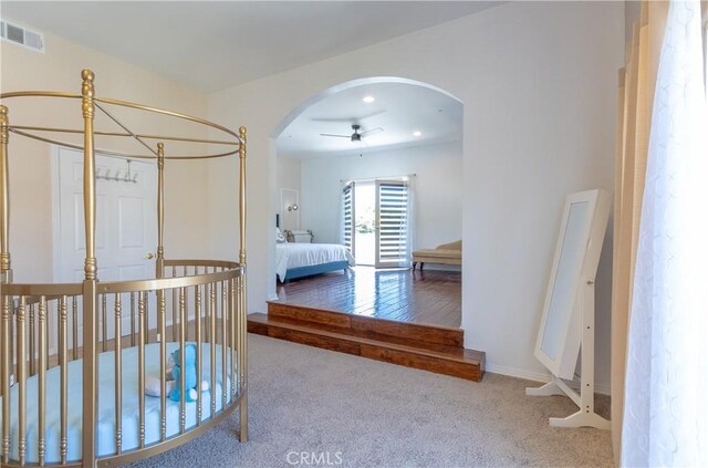 carpeted bedroom with arched walkways, baseboards, and visible vents