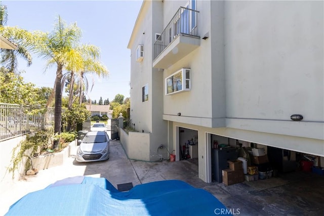 view of side of home featuring fence, stucco siding, and a balcony