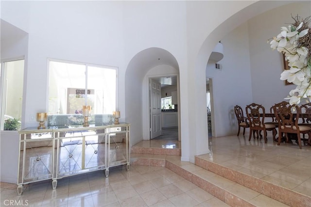 interior space featuring arched walkways, a high ceiling, visible vents, and tile patterned floors