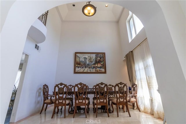 dining room with arched walkways, a high ceiling, and visible vents