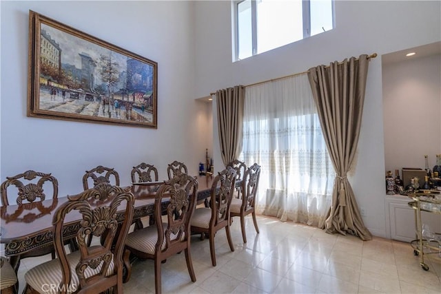 dining room with plenty of natural light, light tile patterned floors, and a high ceiling