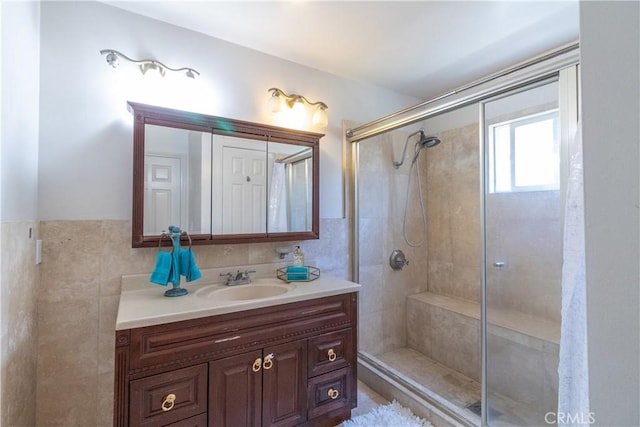 bathroom with tile walls, a shower stall, and vanity