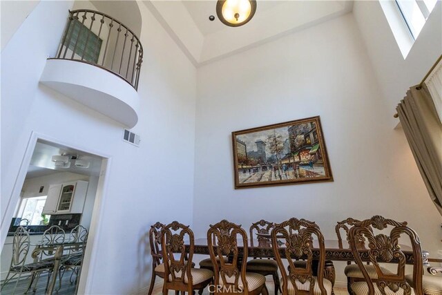 dining area featuring baseboards, visible vents, and a towering ceiling
