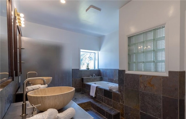 bathroom featuring tile walls, wainscoting, and a soaking tub