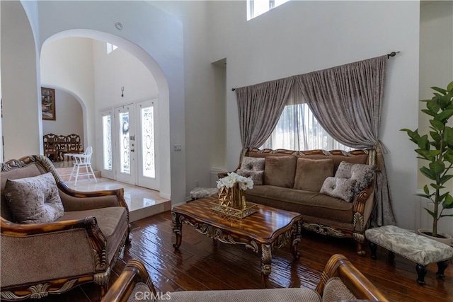 living area with arched walkways, a towering ceiling, and a healthy amount of sunlight