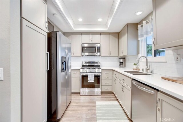 10830 Sundance Dr, Rancho Cucamonga, CA 91730 - kitchen featuring tasteful backsplash, a sink, light wood-type flooring, a raised ceiling, and appliances with stainless steel finishes