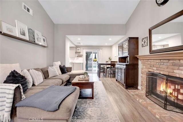 10830 Sundance Dr, Rancho Cucamonga, CA 91730 - living room featuring a brick fireplace, visible vents, and light wood-style flooring