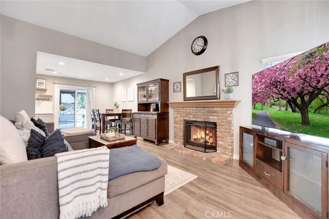 10830 Sundance Dr, Rancho Cucamonga, CA 91730 - living area with high vaulted ceiling, a brick fireplace, and light wood-style flooring