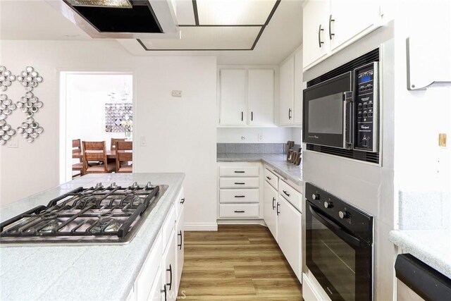 8288 Mercury Dr, Buena Park, CA 90620 - kitchen featuring black appliances, light wood-type flooring, light countertops, and white cabinetry