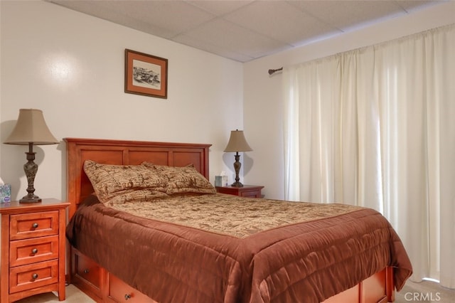 bedroom with light colored carpet and a paneled ceiling