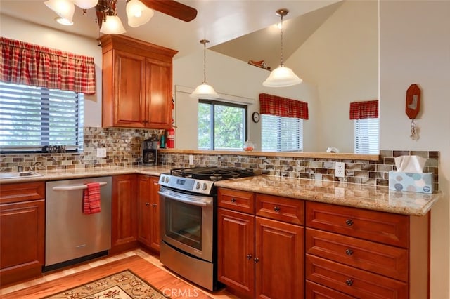 kitchen featuring light wood finished floors, brown cabinets, stainless steel appliances, decorative backsplash, and a ceiling fan