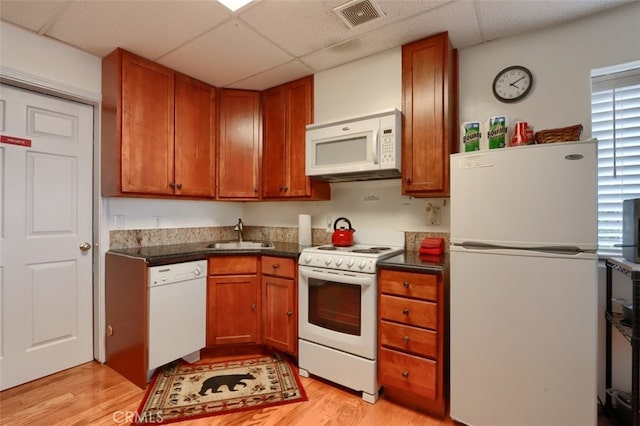 kitchen featuring a sink, dark countertops, visible vents, a drop ceiling, and white appliances