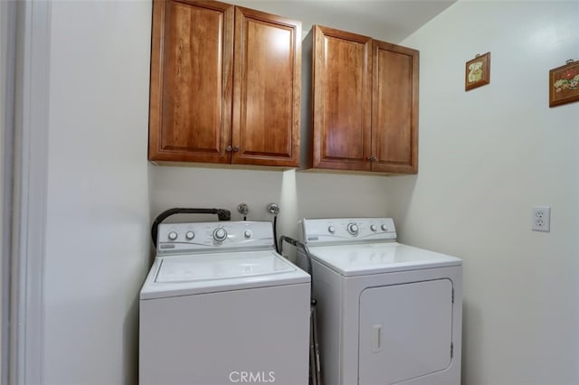 laundry area with separate washer and dryer and cabinet space