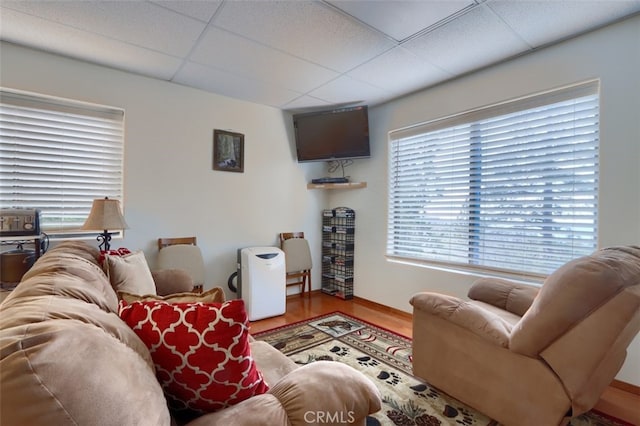 living area featuring baseboards, wood finished floors, and a drop ceiling