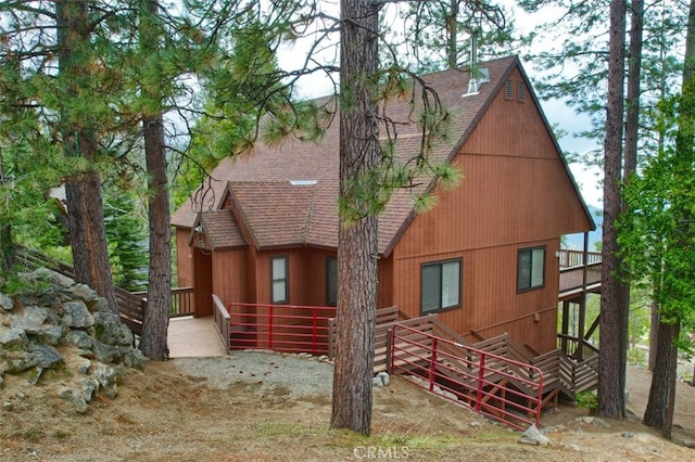back of property featuring a wooden deck and a shingled roof