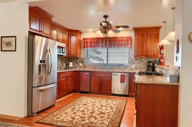 kitchen featuring appliances with stainless steel finishes, light wood-type flooring, a ceiling fan, and a sink