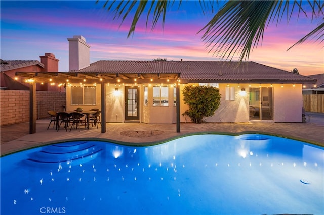 pool at dusk with fence, a patio area, and a fenced in pool