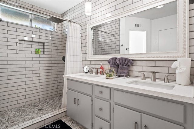 bathroom featuring tasteful backsplash, a stall shower, and a sink