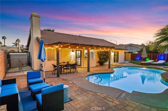 pool at dusk with a gate, a fenced in pool, a fenced backyard, and a patio