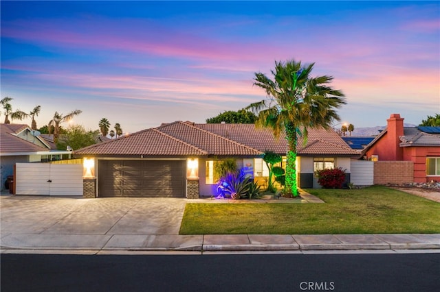 view of front of home with concrete driveway, a front yard, a tiled roof, and a garage