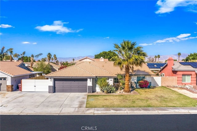 single story home featuring a gate, concrete driveway, a tiled roof, an attached garage, and a mountain view