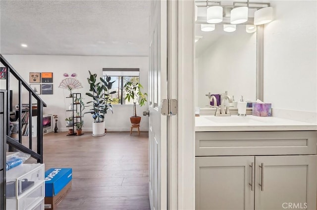 bathroom featuring hardwood / wood-style flooring, vanity, and a textured ceiling