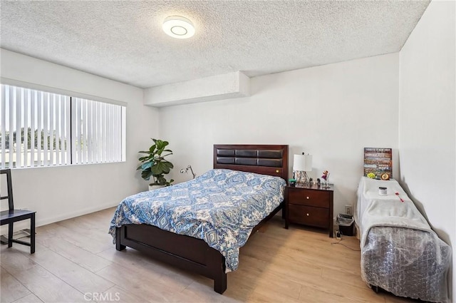 bedroom featuring baseboards, wood finished floors, and a textured ceiling