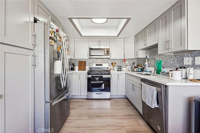 kitchen featuring decorative backsplash, appliances with stainless steel finishes, a sink, and a raised ceiling