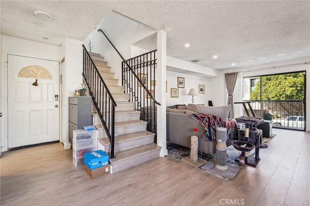 entrance foyer featuring recessed lighting, wood finished floors, a textured ceiling, and stairs