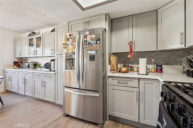 kitchen featuring light wood finished floors, light countertops, stainless steel fridge, and gray cabinets