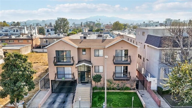 view of front of property featuring a balcony, a mountain view, a residential view, and stucco siding