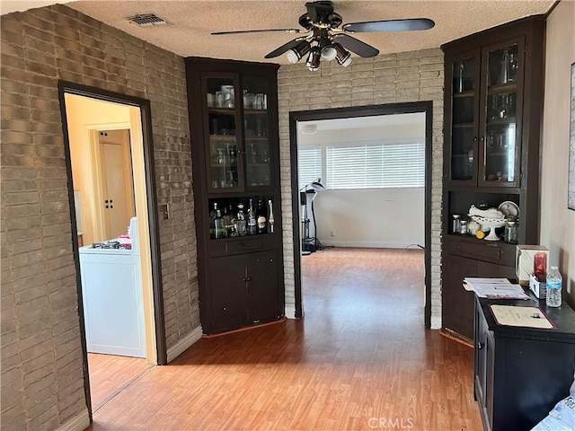 1423 S Poinsettia Ave, Compton, CA 90221 - hallway featuring wood finished floors, brick wall, a textured ceiling, and washer / dryer