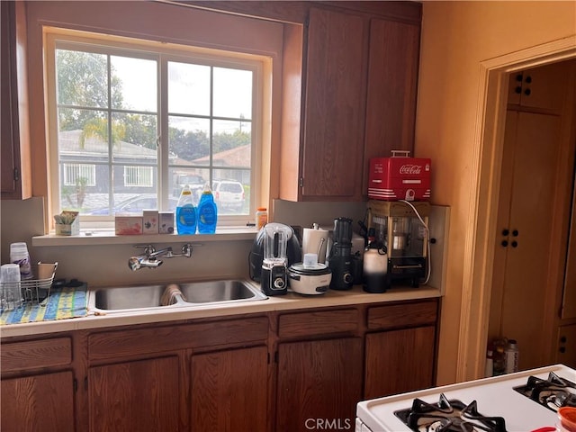 1423 S Poinsettia Ave, Compton, CA 90221 - kitchen with a sink, white gas range oven, and brown cabinets