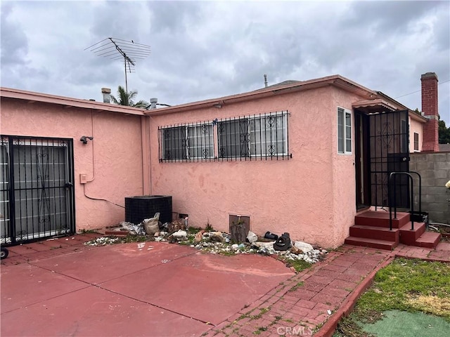 1423 S Poinsettia Ave, Compton, CA 90221 - view of side of home featuring stucco siding, cooling unit, a patio, and a chimney