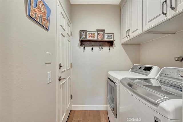 clothes washing area with separate washer and dryer, baseboards, cabinet space, and light wood-style flooring