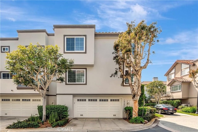 multi unit property with an attached garage, concrete driveway, and stucco siding