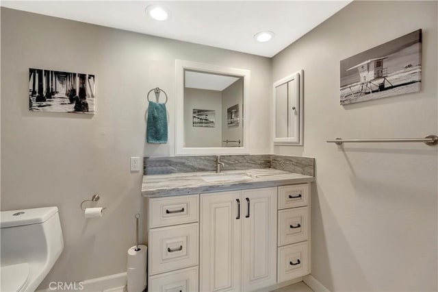 bathroom featuring baseboards, toilet, and vanity
