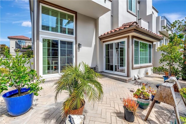 entrance to property with a patio, a tiled roof, and stucco siding