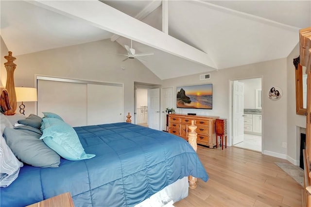 bedroom featuring ensuite bath, light wood-type flooring, a closet, and vaulted ceiling with beams
